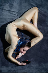 High angle view of woman stretching while using mobile phone