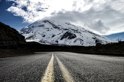 Road amidst snowcapped mountains against sky