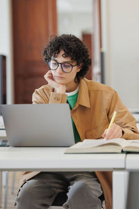 Young woman using laptop while sitting at office