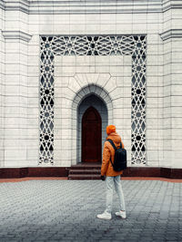 Rear view of woman standing against building