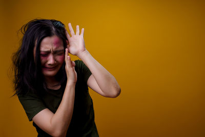 Portrait of a young woman against yellow background