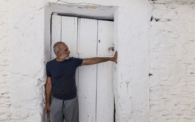 Adult man against white wooden door and white wall