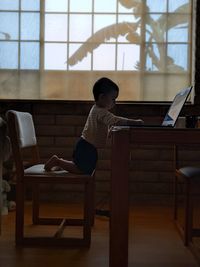 Side view of woman using laptop at home