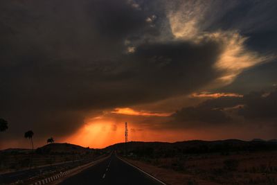 Road by silhouette landscape against sky during sunset