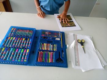 High angle view of child with art and craft equipment on table