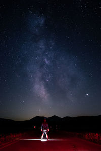 Rear view of man standing against sky at night