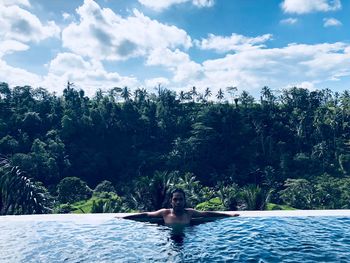 Man relaxing in swimming pool against trees