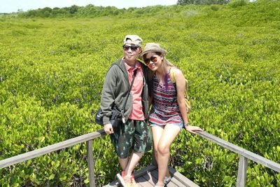 Full length of couple wearing sunglasses while standing against railing and plants 