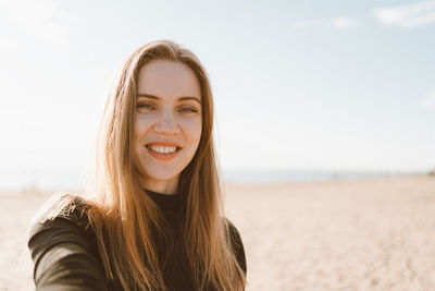 Portrait of smiling young woman standing on beach