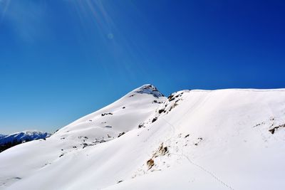 Scenic view of snowcapped mountains against clear blue sky