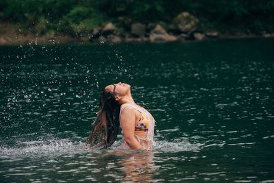 Side view of woman tossing hair in sea