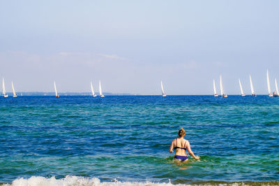 Rear view of woman in bikini at beach against sky
