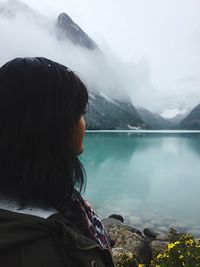 Rear view of woman looking at lake against mountain