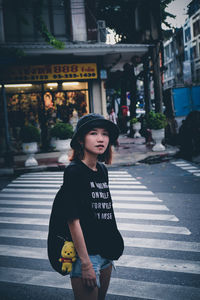 Portrait of young woman standing on street in city 