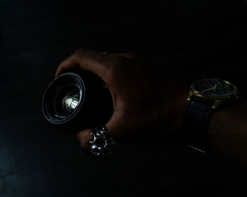 Midsection of man holding camera against black background