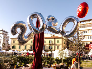 Low angle view of balloons against buildings in city