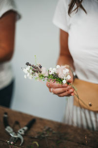 Midsection of woman holding white flower on table