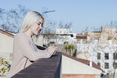 Close-up of smiling woman standing against building