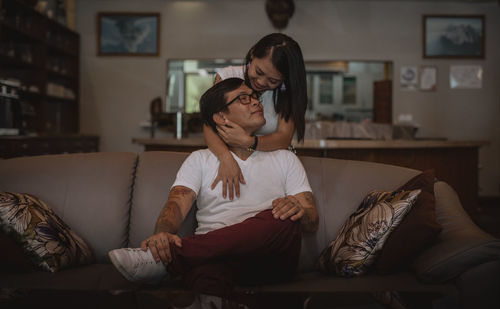 Woman embracing man sitting on sofa at home