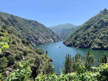 Scenic view of lake and mountains against clear blue sky