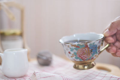Close-up of hand holding tea cup on table