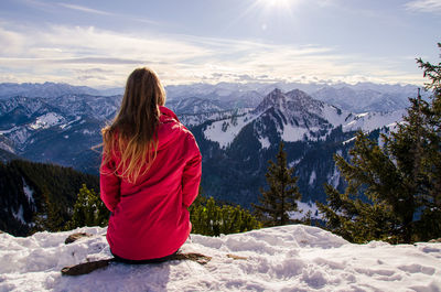 Women with long blond hair looking over panoramic snowcapped mountain view