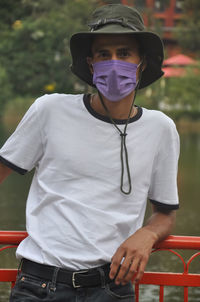 A young guy standing outdoor with wearing face mask during covid-19 with looking at camera 