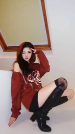 Portrait of young woman sitting against white background