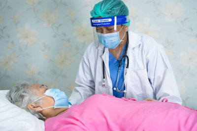 Doctor wearing flu mask examining patient at hospital