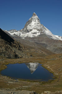 Scenic view of lake and mountains against clear blue sky