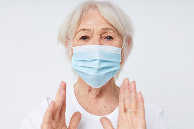 Portrait of young woman wearing mask against white background