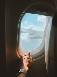 Cropped hand of woman touching window in airplane