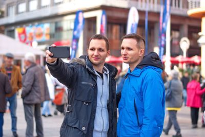 Brother taking selfie while standing on street in city