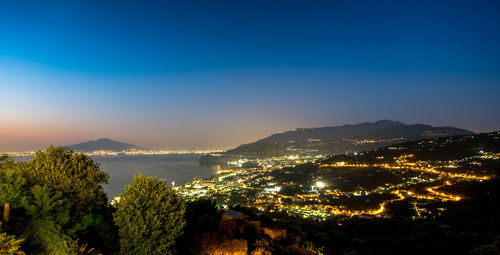 Illuminated cityscape against clear sky at night