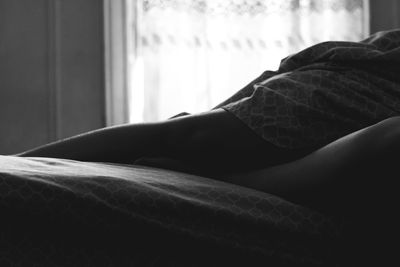 Low section of man relaxing on bed at home