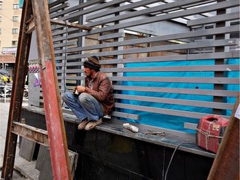 Full length of woman sitting on railing