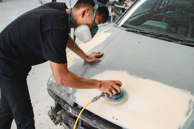 Mechanic wearing mask working on car at garage