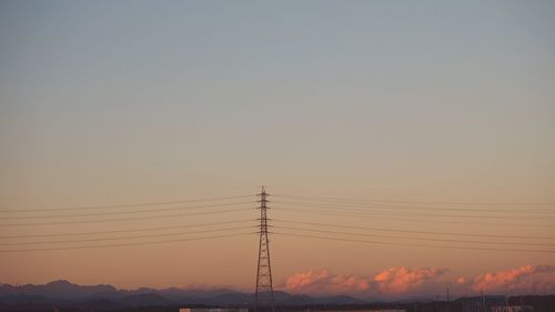 Low angle view of silhouette electricity pylon against clear sky