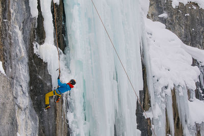 Woman climbing on snowcapped mountain during winter