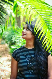 Smiling young woman standing against plants