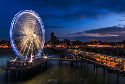 Illuminated ferris wheel in city at night