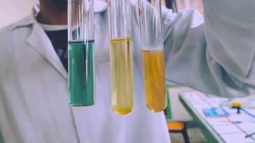 Midsection of scientist with chemicals in test tubes