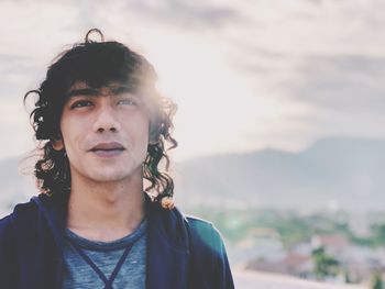 Close-up of smiling young man against cloudy sky