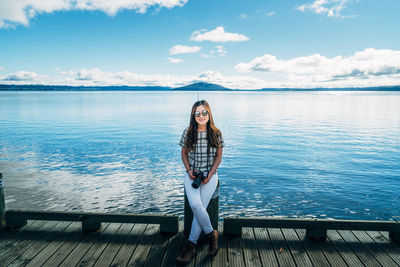 Portrait of young woman standing in sea against sky