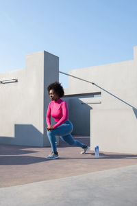 Black sportswoman stretching during training