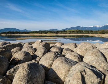 Rocks by lake against blue sky