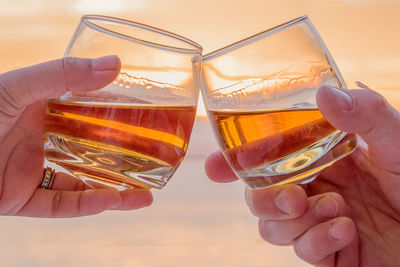Cropped image of hands toasting against sea
