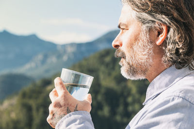 Side view of young man drinking glass