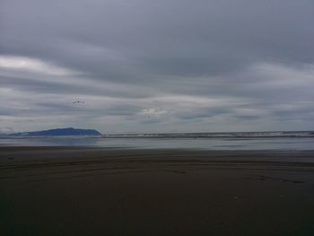 Scenic view of beach against cloudy sky