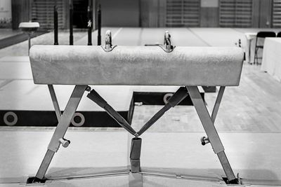 Close-up of empty bench on table against wall in city